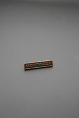 remache metálico cobre envejecido vista frontal con texto Mostazza