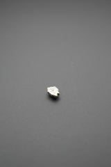 Vista lateral de pasador metálico floral plata sobre superficie gris