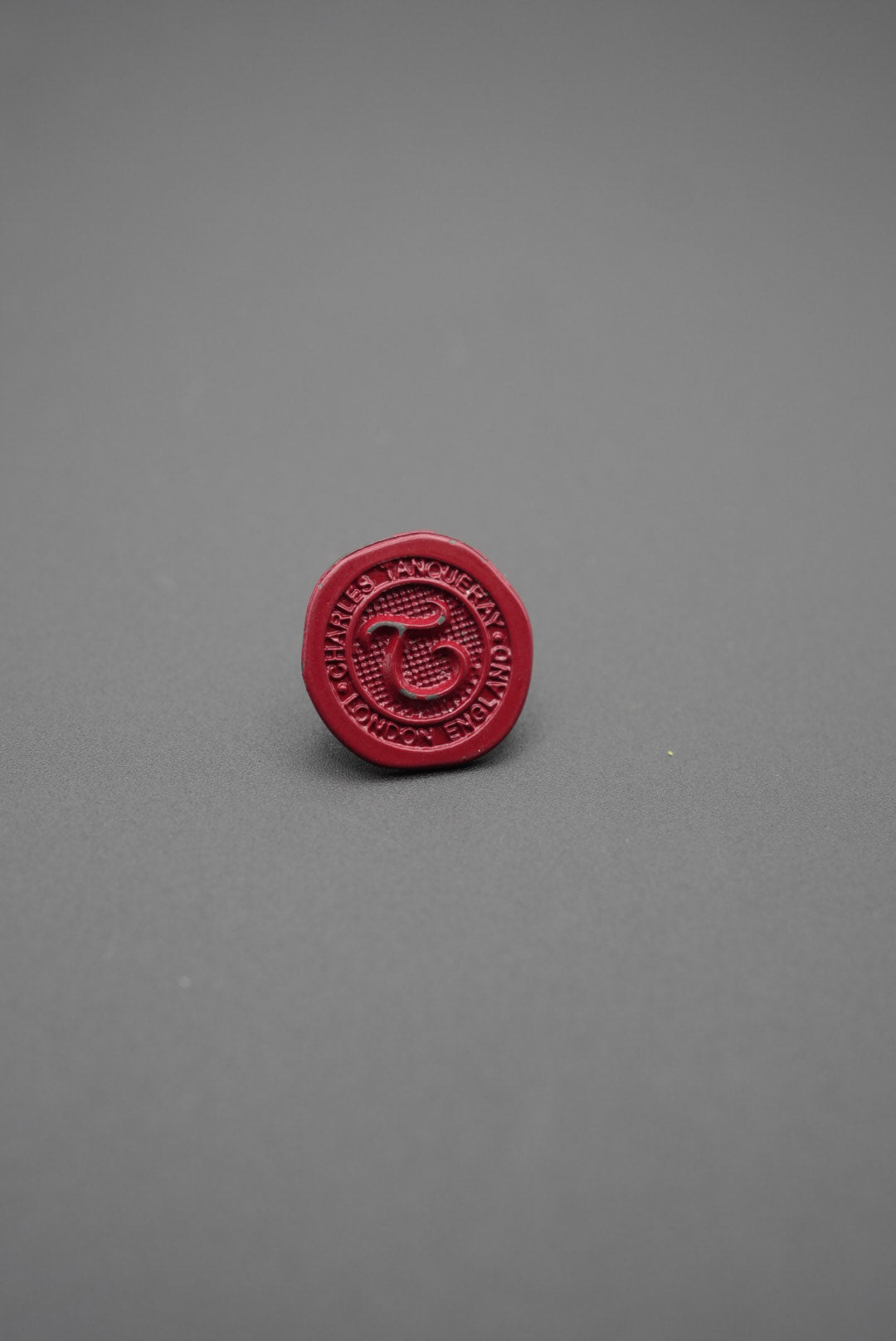 Botón de golpe rojo personalizado con escritura y logo en relieve en fondo gris