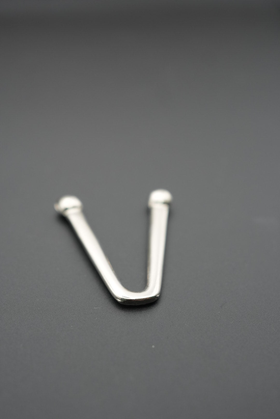 Gancho de metal en V con reflejos de luz en superficie pulida
