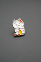 Pin gato Maneki-neko ligeramente desenfocado en fondo gris liso