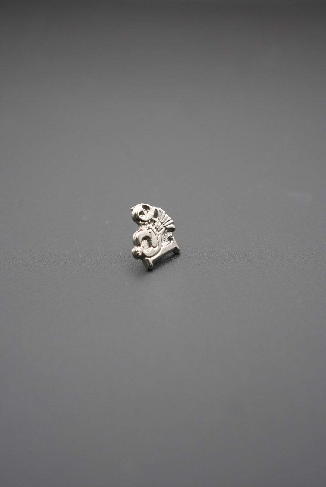 Pin metálico detalle frontal con diseño técnico en metal