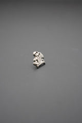 Pin metálico detalle frontal con diseño técnico en metal