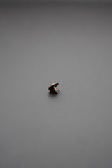 Remache metálico visto de lado sobre fondo gris