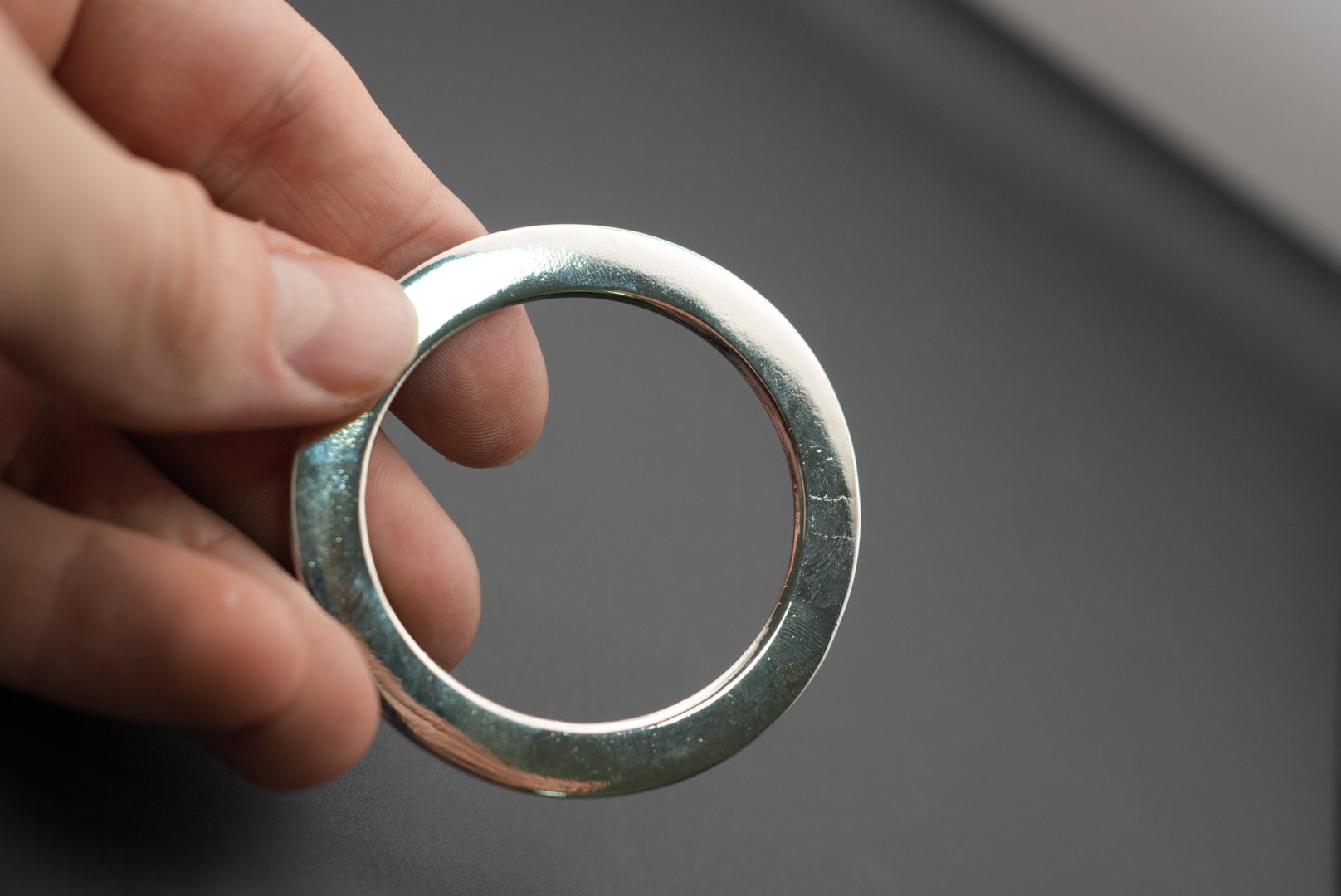 Mano sosteniendo una arandela metálica plana y brillante
