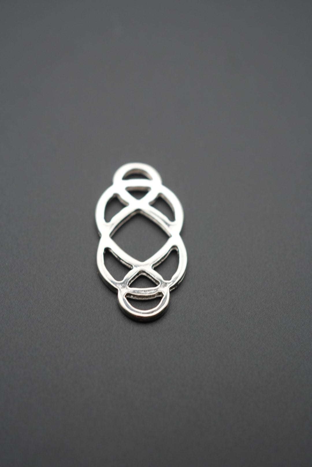 close-up del conector metálico decorativo con diseño entrelazado sobre fondo gris