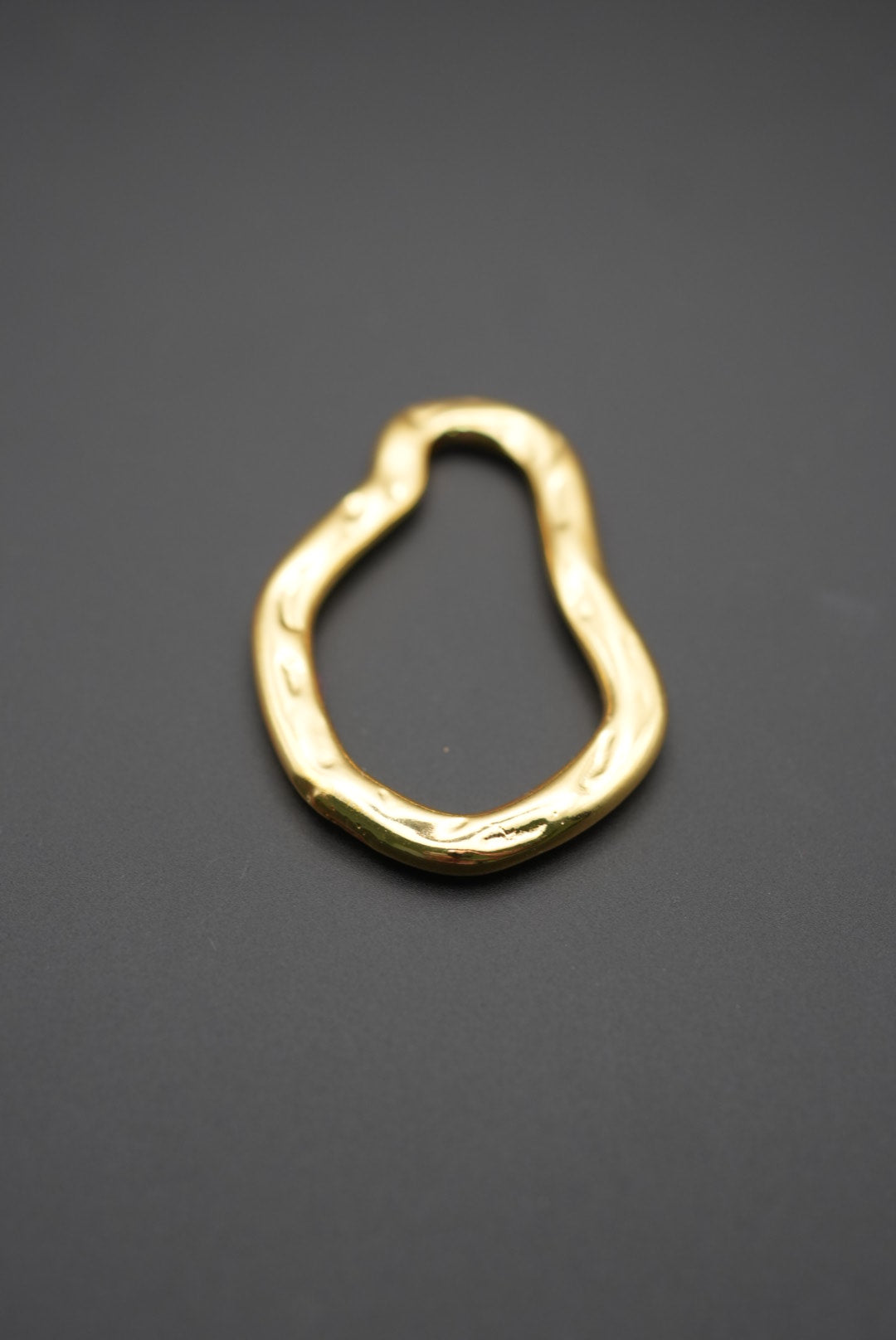 Primer plano de pulsera dorada con acabado brillante y contornos ondulados