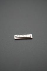 Primer plano de placa metálica FEMMED con acabado brillante sobre fondo gris