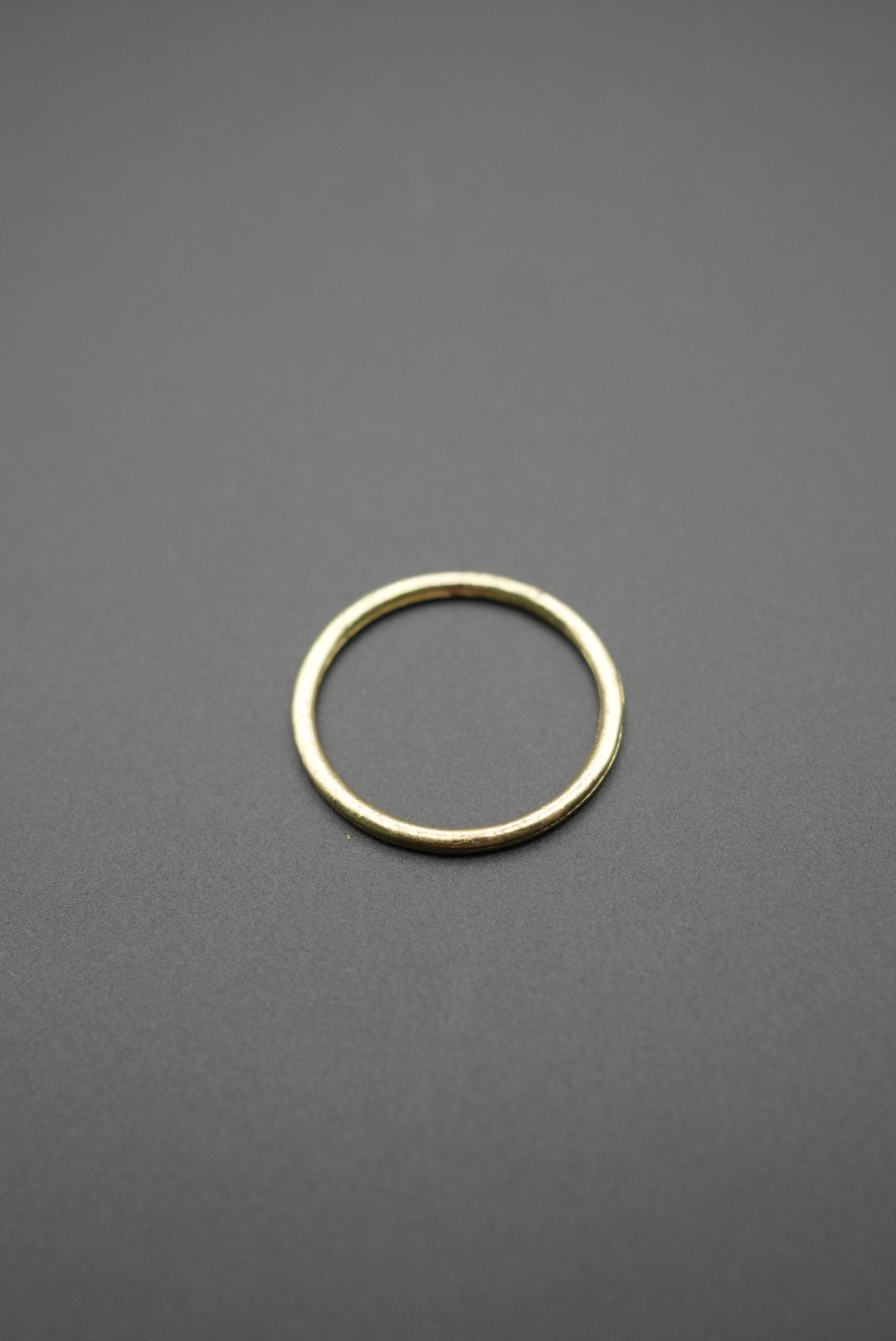 Anillo metálico redondo color dorado con acabado pulido sobre fondo gris