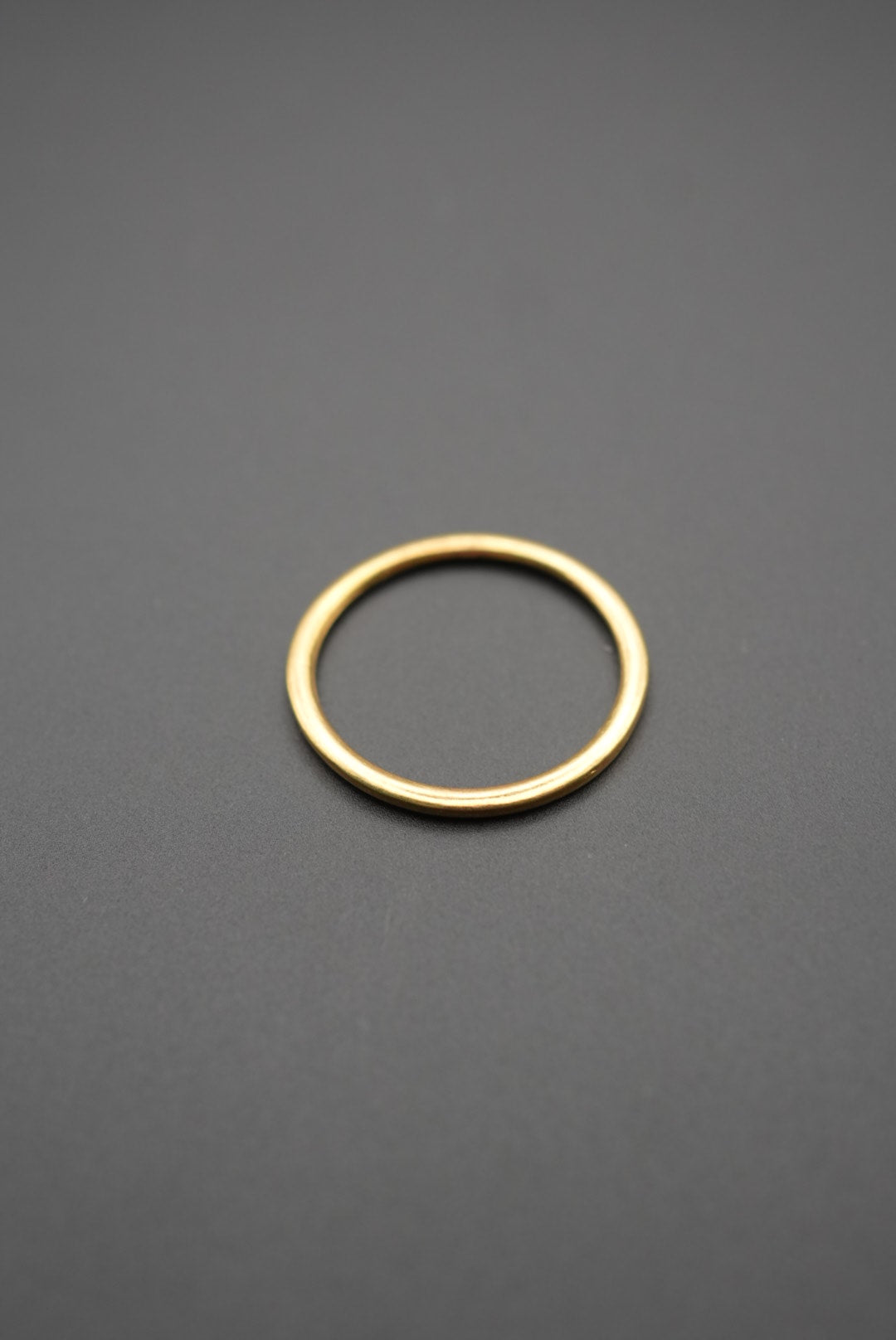 Anillo dorado simple con fondo gris en imagen cercana