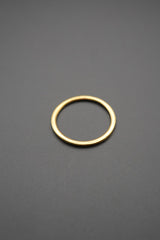 Anillo dorado simple con fondo gris en imagen cercana