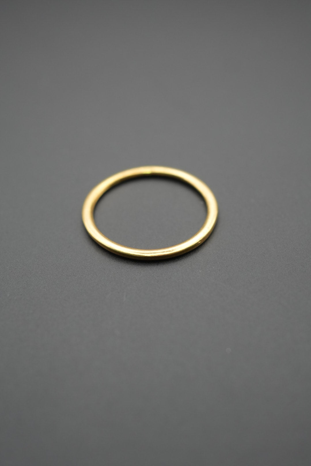 Anillo de diseño sencillo y pulido color dorado sobre fondo gris