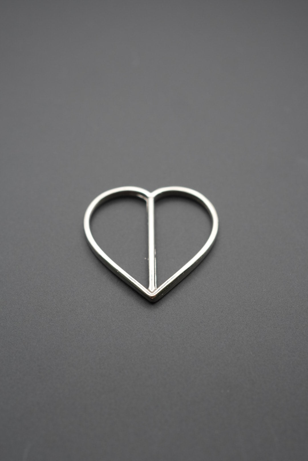 Detalle de hebilla metálica brillante con diseño en corazón