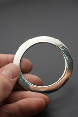 Detalle de arandela metálica sostenida por mano humana, acabado pulido