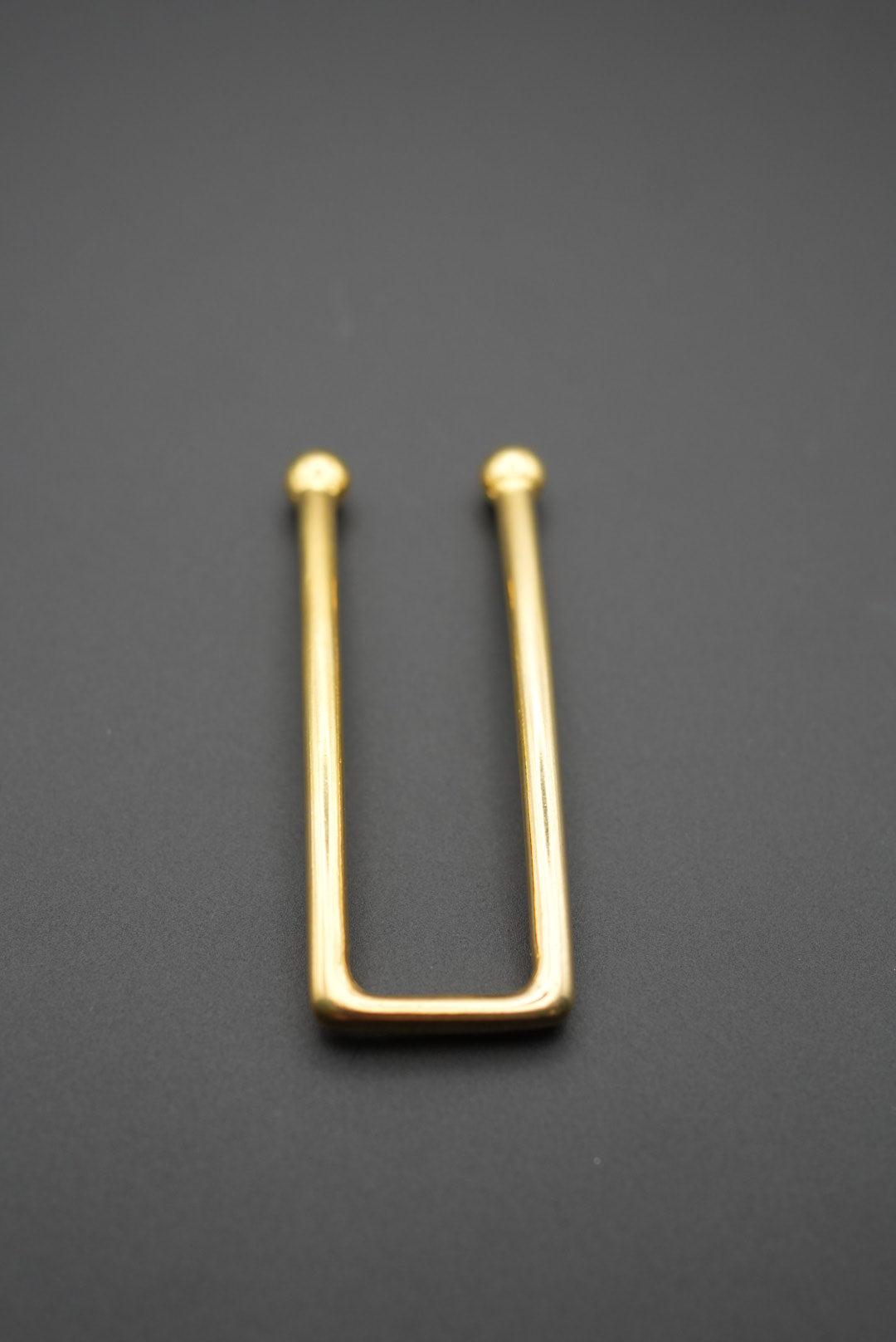 Vista lateral del pasador dorado mostrando su forma rectangular
