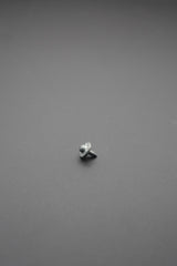 Remache metálico con acabado gris plata visto de frente sobre fondo gris