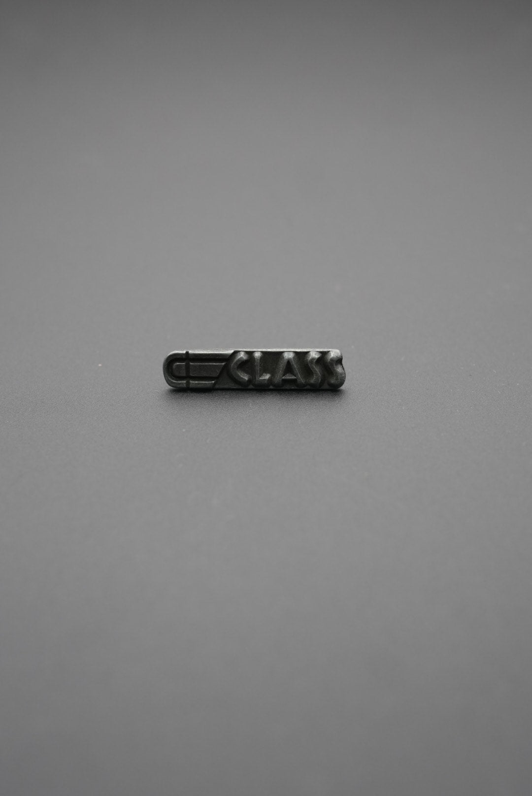 Perspectiva oblicua de etiqueta metálica con la inscripción 'CLASS' destacada