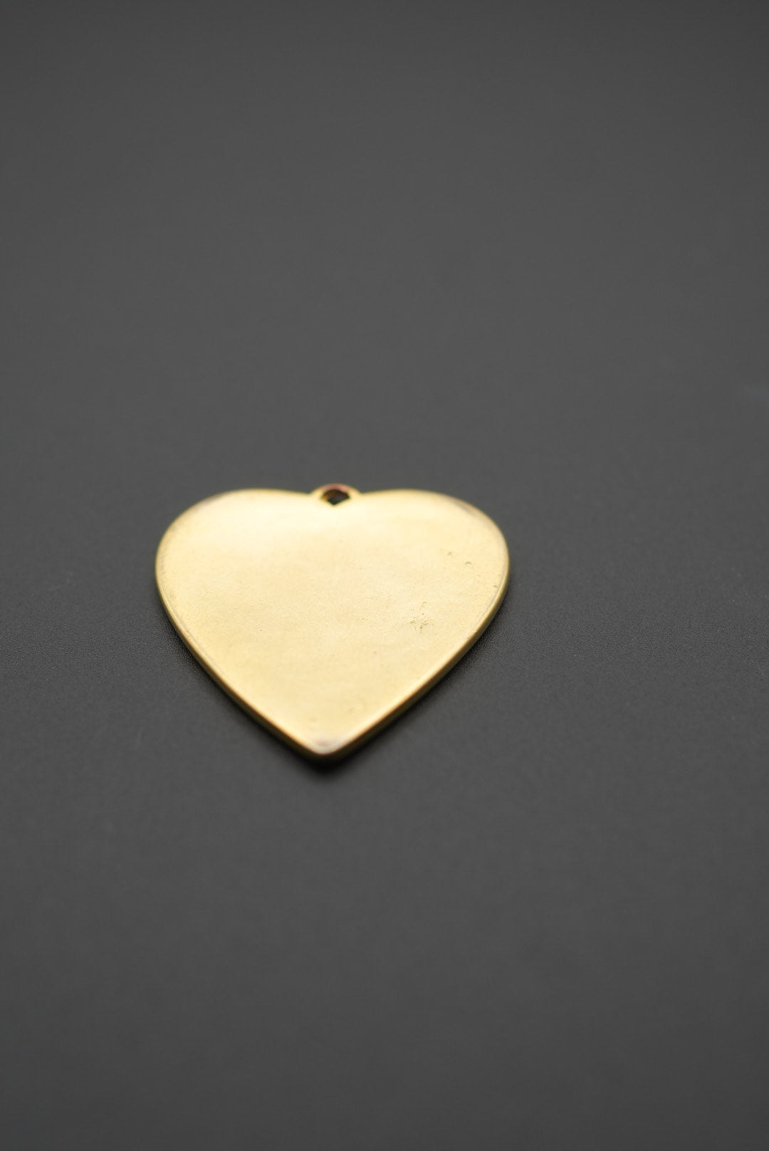 Colgante corazón dorado visto de lado, mostrando su grosor y acabado