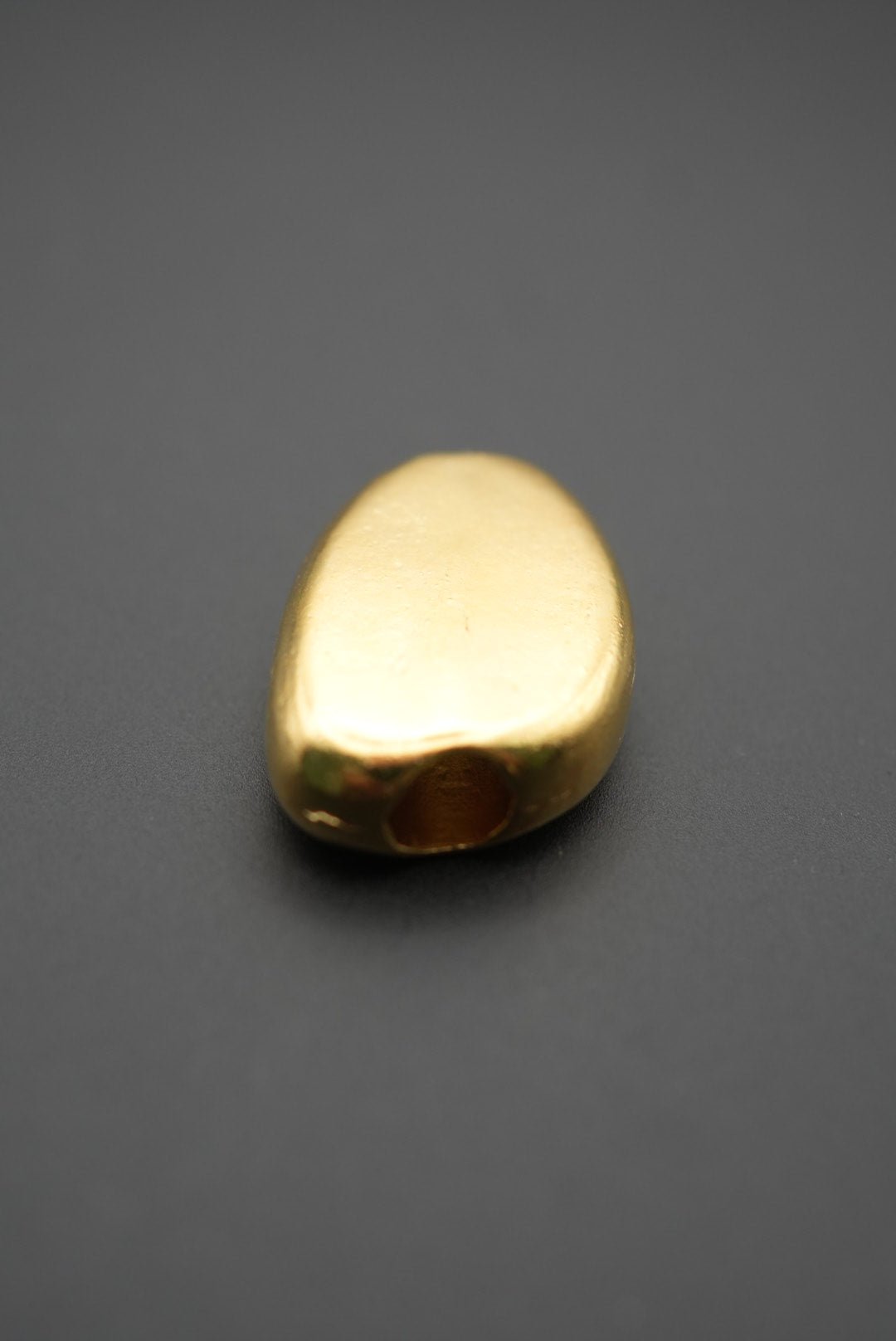 Cuenta dorada mostrando el orificio para ensamble en primer plano