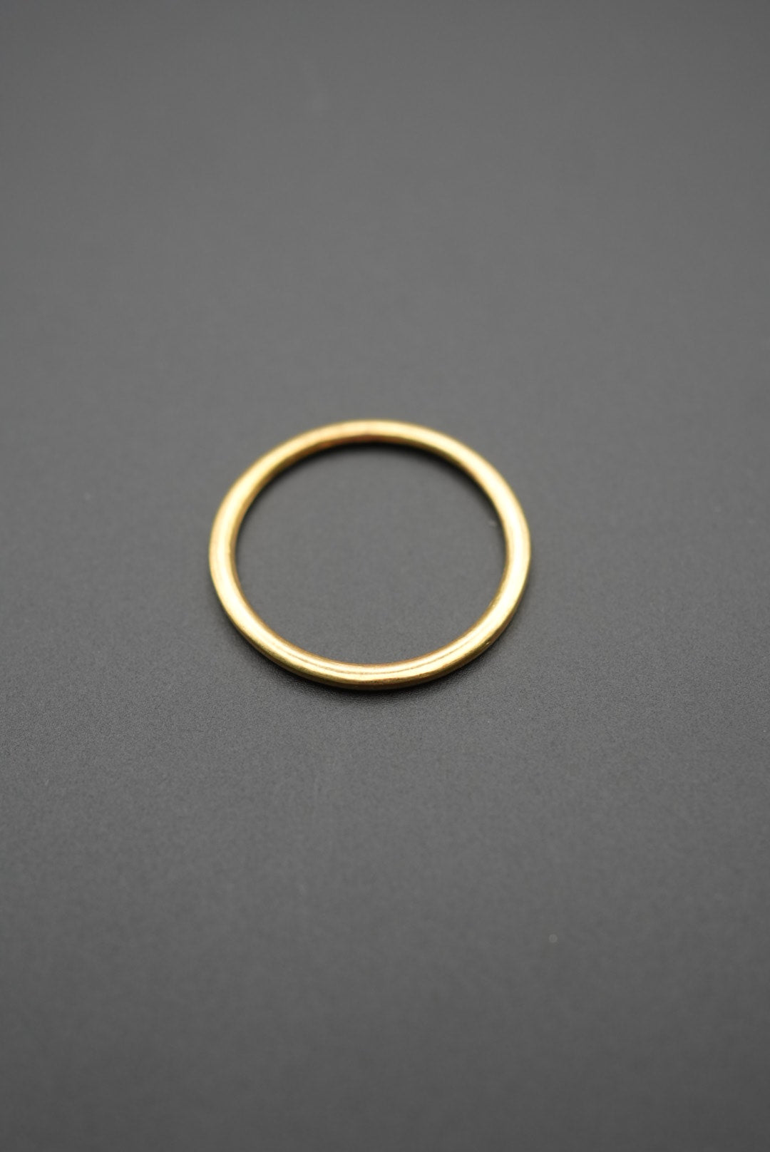 Detalle de anillo dorado minimalista sobre fondo gris