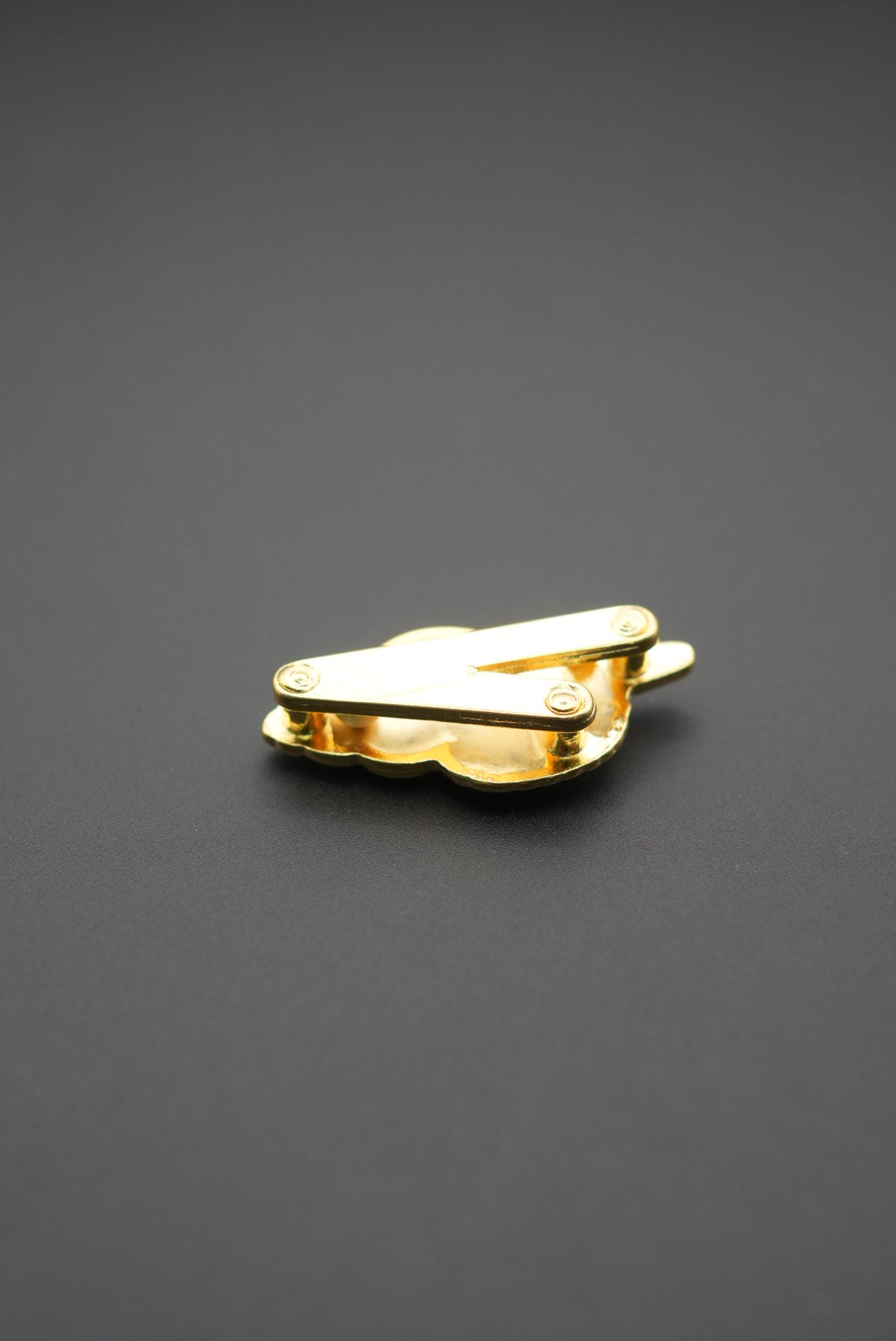 Pin metálico dorado en forma de concha marina con vista detalle trasera del mecanismo